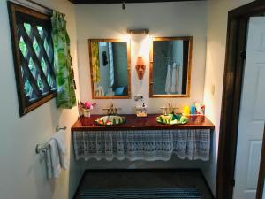 a bathroom with two sinks and two mirrors at Coral Hill Bungalows in Cahuita