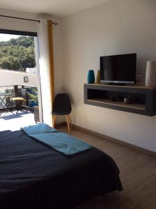 - une chambre avec un lit et une télévision murale dans l'établissement Au bien être, à Bastia
