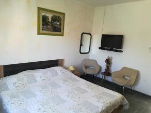 a bedroom with a bed and two chairs and a tv at Guesthouse Porec in Poreč