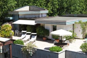 a patio with white chairs and tables and umbrellas at Hotel Numi & Medusa in Cesenatico