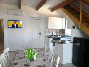 uma cozinha com uma mesa com cadeiras e uma televisão na parede em Il Quadrifoglio em Massa Lubrense