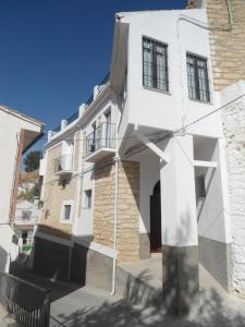 a white house with black windows on a street at Casa de Los Albas, 6p in Montefrío