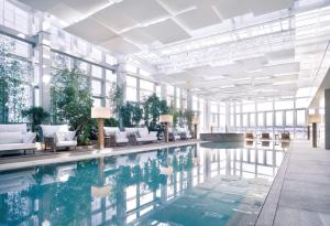 a pool in a building with white furniture and windows at Park Hyatt Busan in Busan