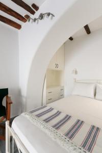 een witte slaapkamer met een bed en een stoel bij CASA NEL BORGO in Naxos Chora