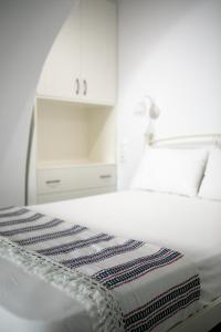 een witte slaapkamer met een bed en een wastafel bij CASA NEL BORGO in Naxos Chora