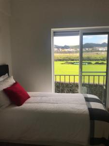 a bed with a red pillow and a large window at CASA SIMBA , where the fun begins in Ponta Delgada