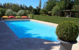 - une piscine dans une cour avec une haie dans l'établissement Les Carmes and spa, au Thor