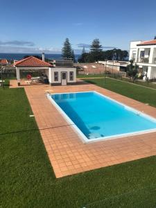 a swimming pool in a yard next to a house at CASA SIMBA , where the fun begins in Ponta Delgada