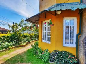 بنغل ليدي هورتون في نوارا إليا: منزل أصفر مع نافذة وبعض الزهور