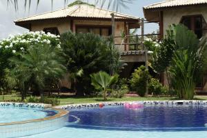 a villa with a swimming pool in front of a house at Pousada Morada dos Ventos in Pipa