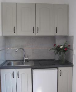 a kitchen with white cabinets and a sink and a vase of flowers at Haus Katerina in Vourvourou