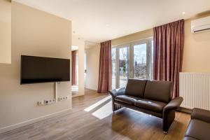 ein Wohnzimmer mit einem Stuhl und einem Flachbild-TV in der Unterkunft Hotel Donny in De Panne
