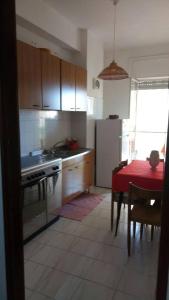 a kitchen with a red table and a kitchen with a stove and refrigerator at Appartamento Piave in Praia a Mare