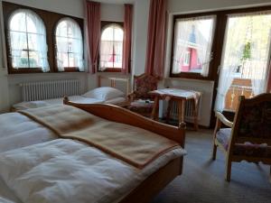 a bedroom with two beds and chairs and windows at Gästehaus Rössle in Rötenbach