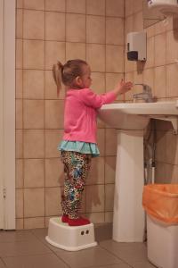 a little girl standing on a sink in a bathroom at Kihnu Sadama Öömaja in Lemsi