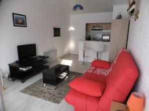 a living room with a red couch and a television at residence Les Canaries in Le Pouliguen