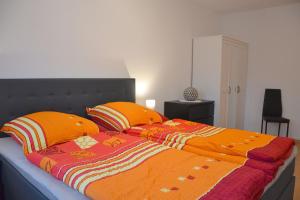 Una cama con dos almohadas naranjas encima. en Ferienhaus Leonie, en Barth