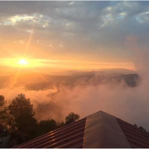 a view of the sun rising above the clouds at Meraki - Entire 3BHK Villa With Himalayan Views in Rānīkhet