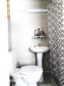a white bathroom with a toilet and a sink at APPARTEMENT MAKEPE BM 2 in Douala