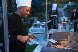 Un homme cuisine de la nourriture sur un grill dans l'établissement Grand Hotel Il Ninfeo, à Gaète