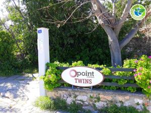 a sign that reads point turn twins in front of flowers at Point Twins Apartments in Vrontados