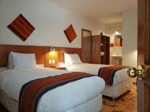 a hotel room with two beds and a bathroom at Mantu Boutique in Machu Picchu