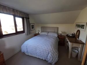 a bedroom with a bed and a desk and a window at Thornham Cottage in Ivybridge