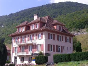 een groot roze gebouw met een bruin dak bij Auberge Pour Tous in Vallorbe