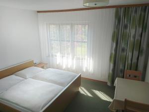 a bedroom with a white bed and a window at Gästehaus Gabriel in Illmitz