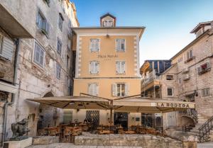 um edifício com guarda-sol, mesas e cadeiras em Plaza Marchi Old Town - MAG Quaint & Elegant Boutique Hotels em Split