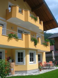 a yellow building with a balcony with tables and chairs at Maria's Platzl Wagrain in Wagrain
