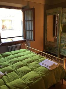 - un lit vert dans une chambre avec une fenêtre et un miroir dans l'établissement Accogliente bilocale centro storico, à Arezzo