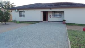 a brick driveway in front of a white house at Kandjo's Bed and Breakfast in Palatswe
