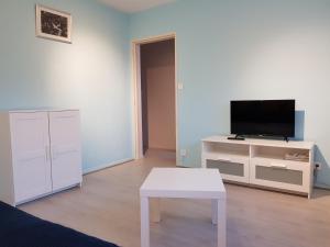Una sala de estar con un televisor y una mesa blanca. en Le Bellevue, en Colmar