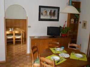 una sala da pranzo con tavolo e TV di Appartamenti Donini Marco a Molveno