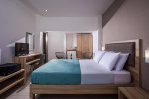 Dormitorio con cama, escritorio y TV en Thania Seaside Smotel - Adults Only, en Agia Pelagia