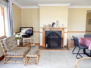 a living room with a fireplace and a tv at Mountain Mist in Bettyʼs Bay