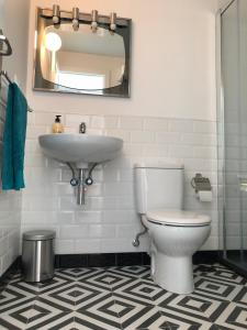 Un baño con lavabo, inodoro y espejo. en El Balcón de Rosita, en Morche