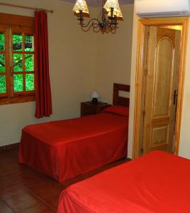 a bedroom with two beds with red sheets at La Noguera in Palomera
