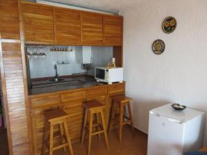 a kitchen with a sink and a microwave and stools at Panorama 29 in Miami Platja