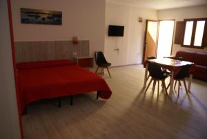 a bedroom with a red bed and a table and chairs at casa mariolu 2 in Cala Gonone