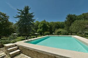 a swimming pool with a stone wall around it at Le Prieuré La Ferme in Souillac