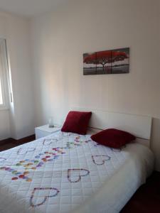 Una cama blanca con almohadas rojas en un dormitorio en Valassina milano apartment, en Milán
