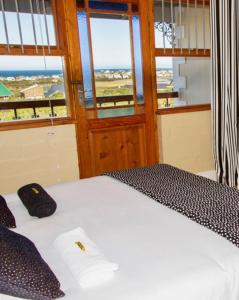 a bedroom with a white bed with a window at Mountain Mist in Bettyʼs Bay