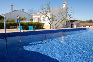 a swimming pool with a blue tile floor and a house at monte da boa fé in Estremoz