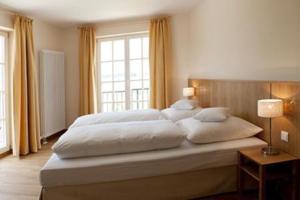 a large white bed in a bedroom with a window at Gutshotel Odelzhausen in Odelzhausen