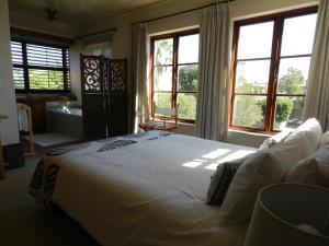 a bedroom with a large white bed with windows at Sunset at Diluta in Cape Town