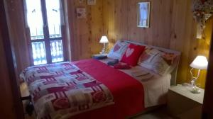 a bedroom with a bed with a red and white blanket at Baita Valtellina in Teglio