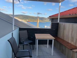 a table and chairs on a balcony with a view of the water at Apartamentos Corcubión in Corcubión