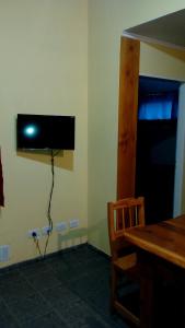 a television on a wall in a room with a table at Departamentos de Alquiler Turistico: Familia Eguren in San Carlos de Bariloche